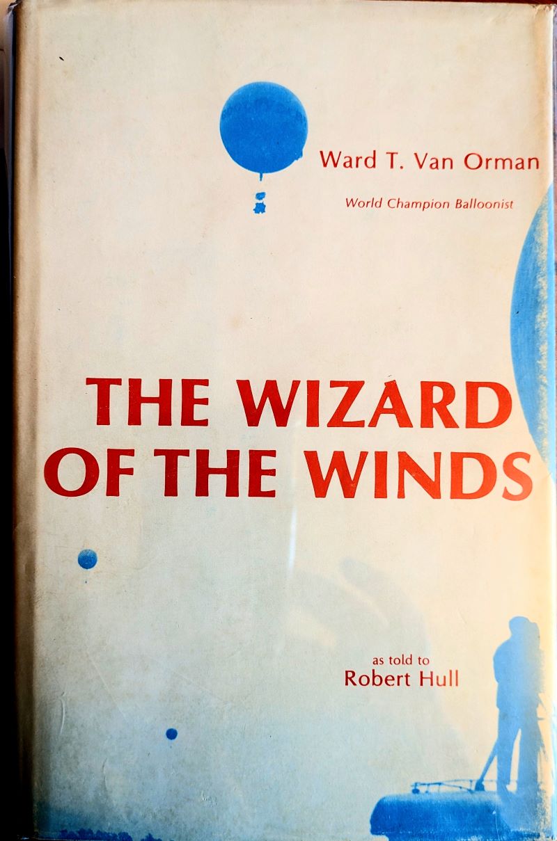 Picture of book cover showing blue gas balloon airborne high in a pale blue sky with two much smaller balloons further away